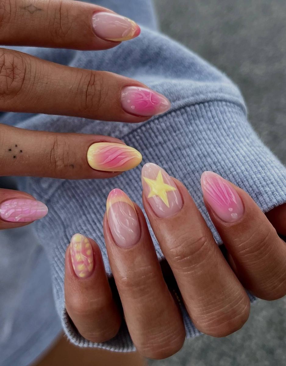 Pink and yellow hand-painted nail art, including a star and swirl design